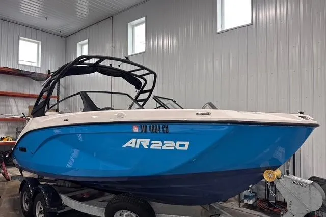 Slide: The Image of 2023 Yamaha Boats AR220 in a garage, blue hull, on a trailer. - 2