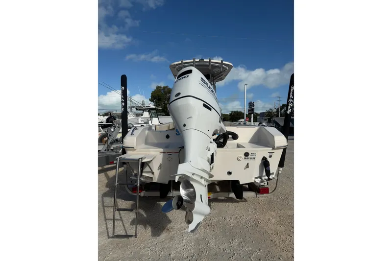 Slide: The Image of 2022 Carolina Skiff 23 UE boat with powerful outboard motor, parked on gravel. - 11