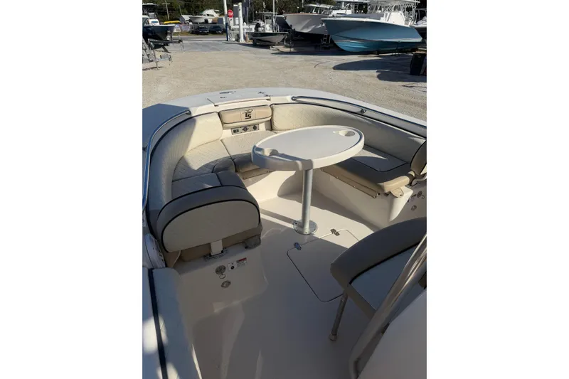 Slide: The Image of 2022 Carolina Skiff 23 UE boat interior with seating and table, parked outdoors. - 23