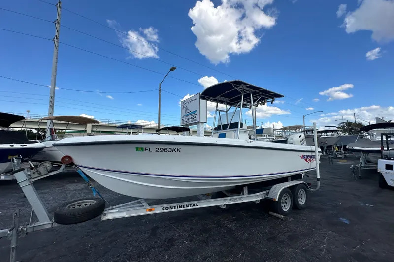 The Image of 1998 Bluewater 2150 boat on trailer under blue sky at dealership. - 0