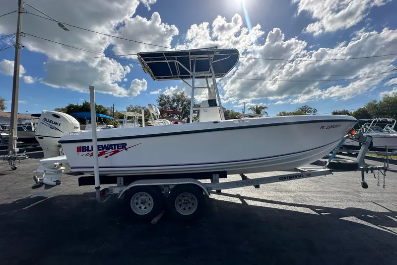 Slide: The Image of 1998 Bluewater 2150 boat on trailer under a partly cloudy sky. - 3