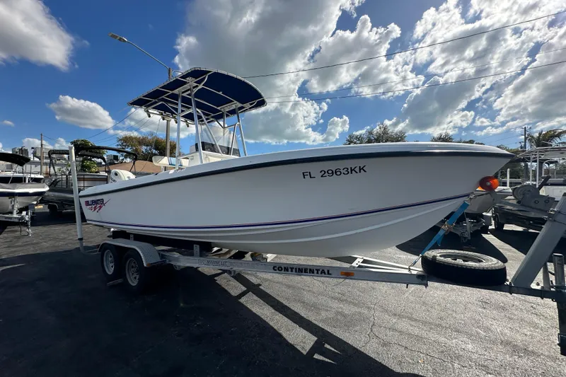 Slide: The Image of 1998 Bluewater 2150 boat on trailer under cloudy sky. - 4
