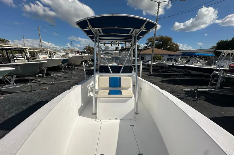 Slide: The Image of 1998 Bluewater 2150 boat with blue canopy, docked under a clear sky. - 8