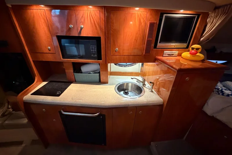 Slide: The Image of 2006 Cruisers Yachts 300 Express interior kitchen with microwave, sink, and wooden cabinetry. - 29