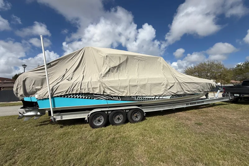 Slide: The Image of Covered 2016 Extreme Boats XC 38 Express on trailer, parked on grass under blue sky. - 24
