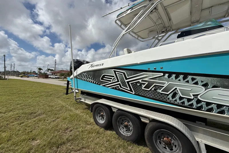 Slide: The Image of 2016 Extreme Boats XC 38 Express on trailer, vibrant design, parked on grass under cloudy sky. - 42