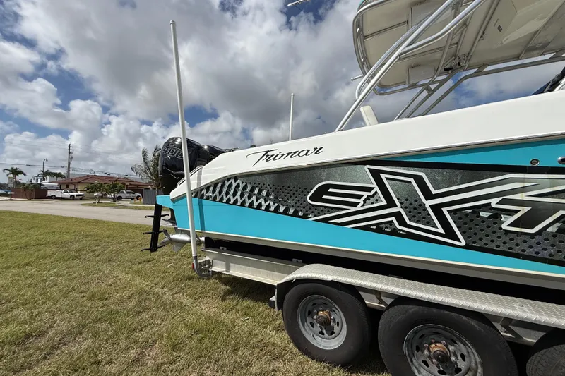 Slide: The Image of 2016 Extreme Boats XC 38 Express on trailer, vibrant design, parked on grass under cloudy sky. - 43