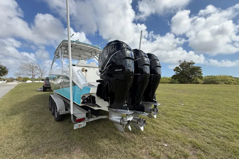 Slide: The Image of 2016 Extreme Boats XC 38 Express on trailer with triple outboard motors, parked on grass. - 50