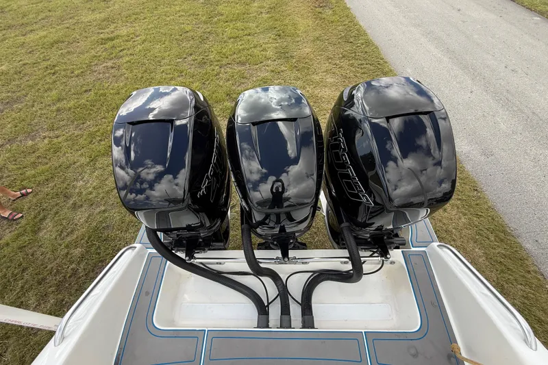 Slide: The Image of Triple outboard motors on a 2016 Extreme Boats XC 38 Express, reflecting sky and clouds. - 99
