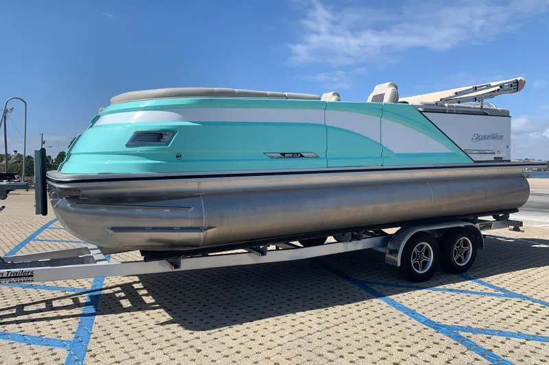 The Image of 2024 Silver Wave 2210CLS pontoon boat on trailer, parked in sunny marina. - 1