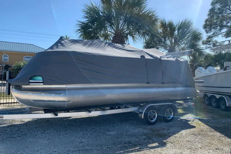 Slide: The Image of 2024 Silver Wave 2210CLS pontoon boat covered on a trailer, parked outdoors. - 37