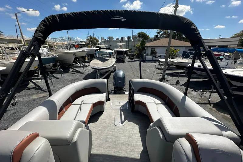 Slide: The Image of 2022 Bennington 22 L Quad Bench pontoon boat with spacious seating, docked under sunny skies. - 10