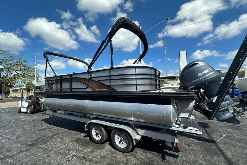 Slide: The Image of 2022 Bennington 22 L Quad Bench pontoon boat on trailer under blue sky. - 2