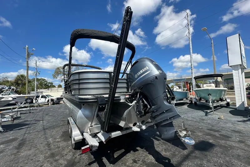 Slide: The Image of 2022 Bennington 22 L Quad Bench pontoon boat with Yamaha outboard motor, parked outdoors. - 3