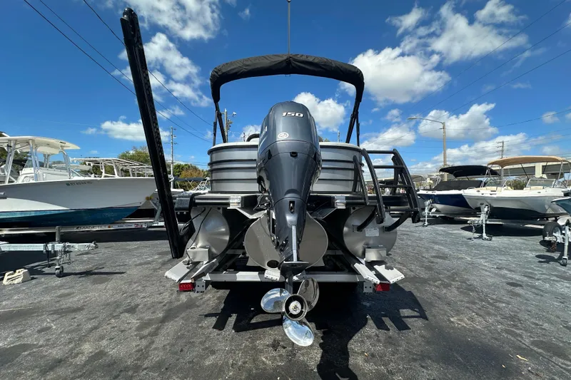 Slide: The Image of 2022 Bennington 22 L Quad Bench pontoon boat with powerful outboard motor, parked outdoors. - 4