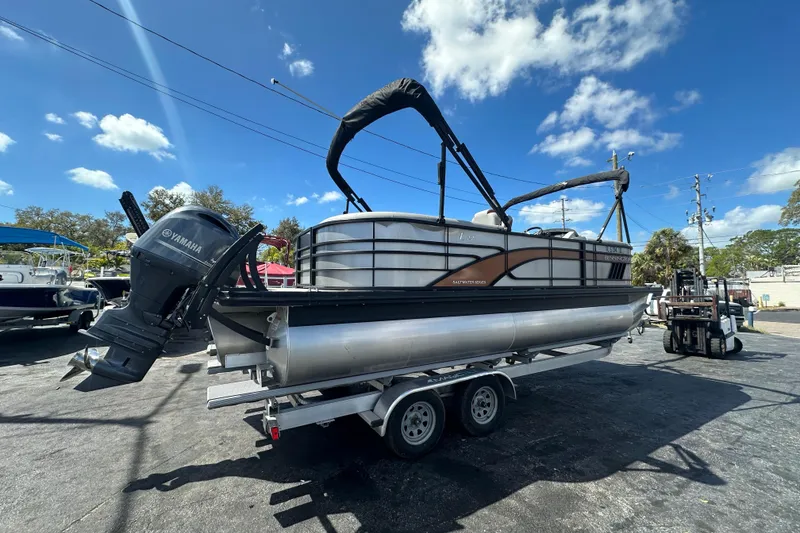 Slide: The Image of 2022 Bennington 22 L Quad Bench pontoon boat on trailer under clear blue sky. - 7