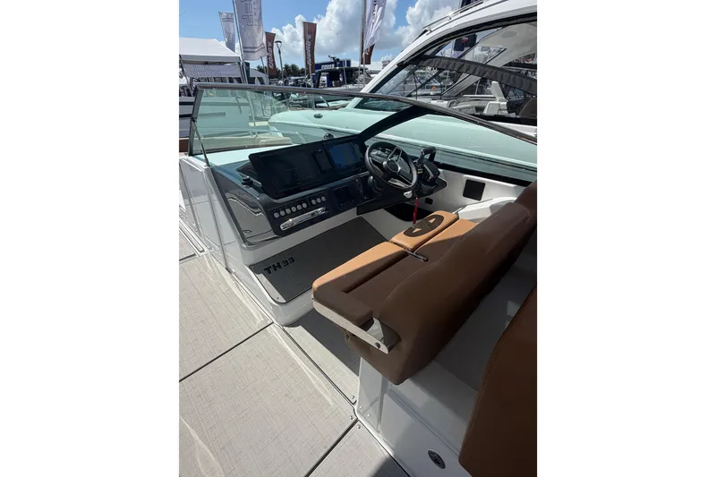 Slide: The Image of 2026 Jeanneau TH33 boat interior with modern dashboard and brown seating. - 7