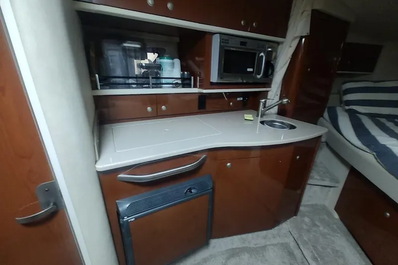 Slide: The Image of 2008 Sea Ray Sundancer 310 interior kitchen with microwave, sink, and storage cabinets. - 14