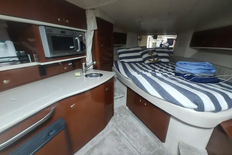 Slide: The Image of 2008 Sea Ray Sundancer 310 interior with kitchenette and cozy striped bedding. - 15