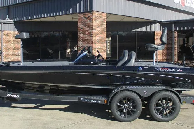 The Image of 2025 Triton 20XP boat with sleek black design on a trailer outside a building. - 1