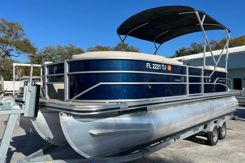 Slide: The Image of 2023 Cypress Cay Seabreeze 232 pontoon boat on trailer, blue and silver design. - 4