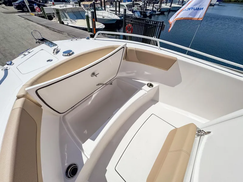 Slide: The Image of 2025 Edgewater 208CC boat interior with seating and storage, docked by the water. - 18