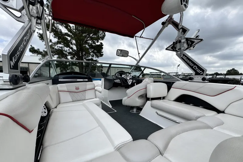 Slide: The Image of 2011 MasterCraft X25 boat interior with white seating and red accents under a cloudy sky. - 10