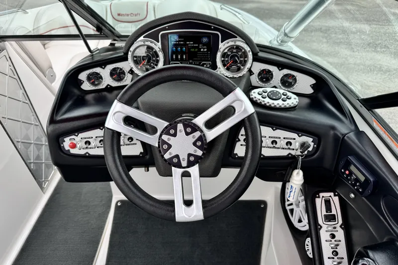 Slide: The Image of Steering wheel and dashboard of 2011 MasterCraft X25 boat, featuring modern controls and gauges. - 13