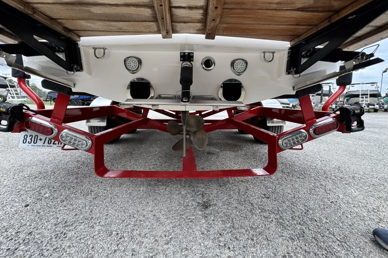Slide: The Image of Rear view of 2011 MasterCraft X25 boat on red trailer, showcasing propeller and lights. - 19
