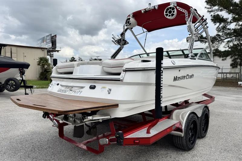 Slide: The Image of 2011 MasterCraft X25 boat on red trailer, featuring a sleek design and wakeboard tower. - 3
