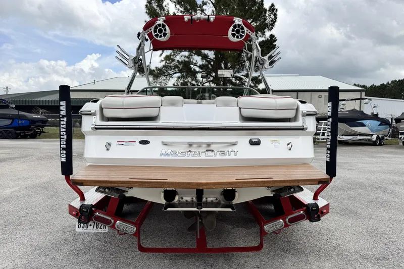 Slide: The Image of 2011 MasterCraft X25 boat, rear view, white with red accents, parked outdoors. - 4