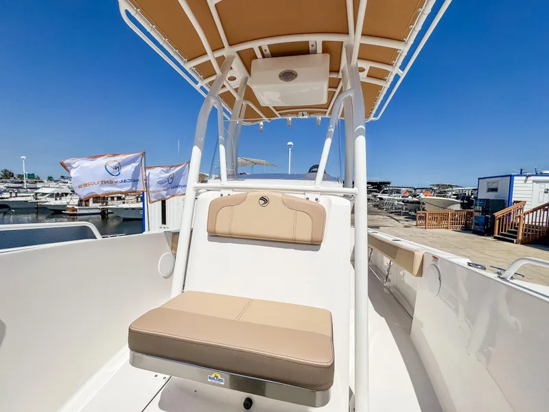 Slide: The Image of 2025 Edgewater 208CC boat interior with tan seating and canopy at marina. - 21