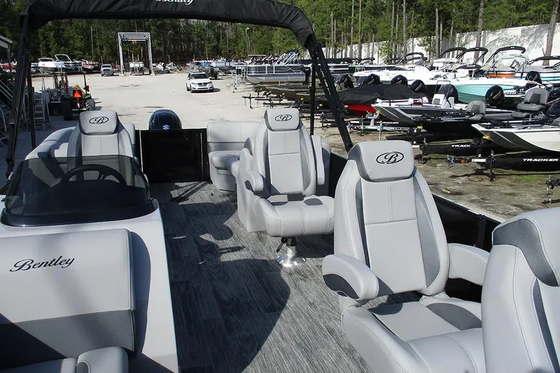 Slide: The Image of 2026 Bentley Pontoons Legacy 243 DL Navigator with luxurious seating in a boat showroom. - 10
