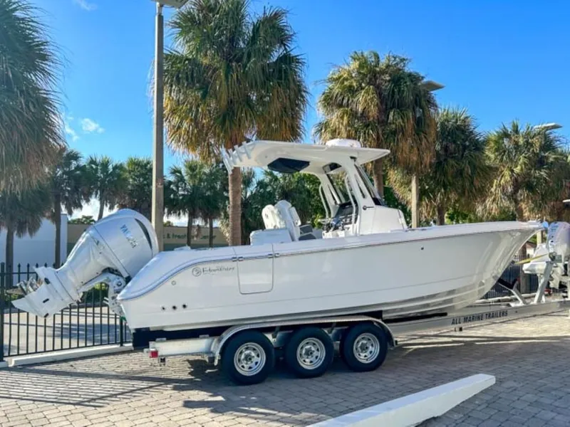 Slide: The Image of 2025 Edgewater 262CC boat on trailer, parked near palm trees under a clear blue sky. - 3