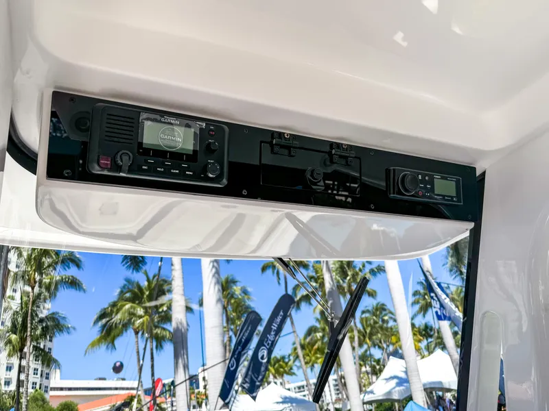 Slide: The Image of 2025 Edgewater 262CC boat dashboard with electronic controls, palm trees in the background. - 7
