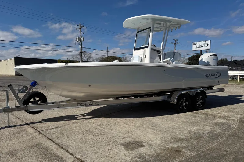 The Image of 2026 Robalo 246 Cayman boat on trailer under clear blue sky. - 1