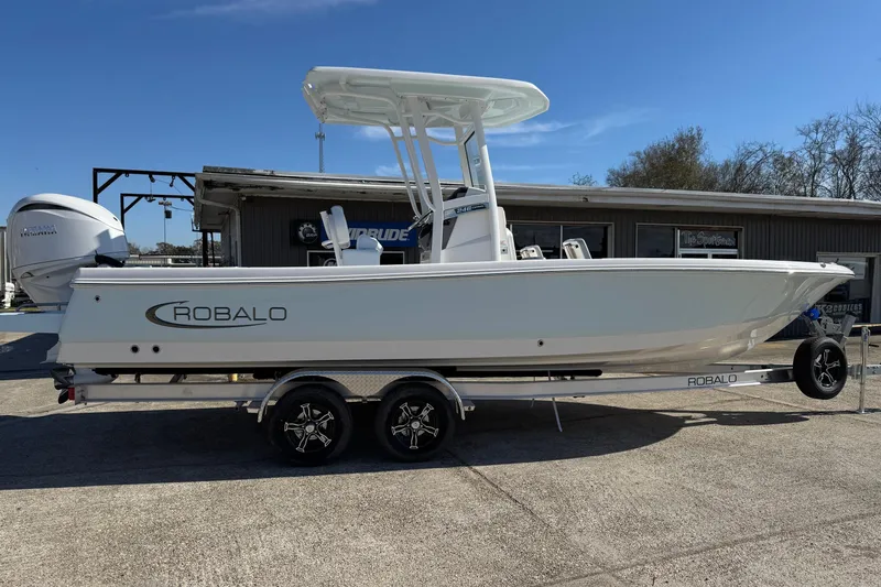 Slide: The Image of 2026 Robalo 246 Cayman boat on trailer, parked outdoors under clear blue sky. - 5