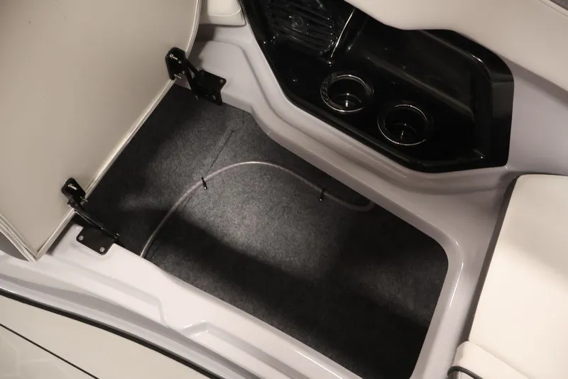 Slide: The Image of 2026 Yamaha Boats 252XE interior storage compartment with cup holders and carpeted flooring. - 23