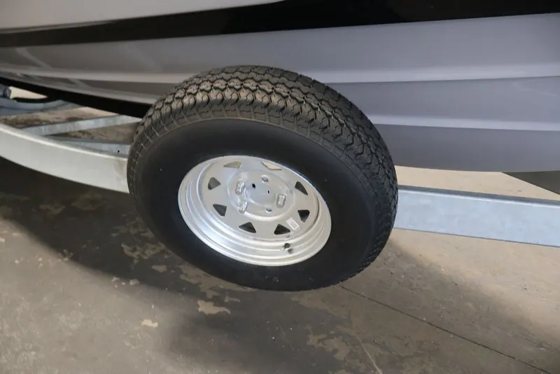 Slide: The Image of Trailer wheel of a 2026 Yamaha Boats 252XE, showcasing sturdy tire and metal rim. - 37