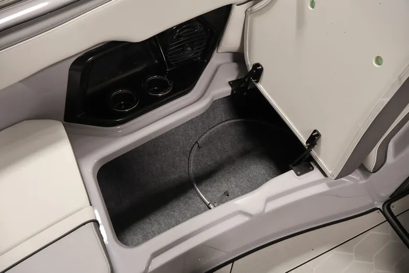 Slide: The Image of Open storage compartment in 2026 Yamaha Boats 252XE, featuring cup holders and sleek design. - 22