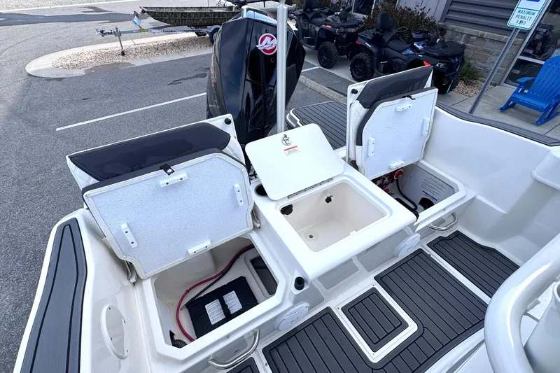 Slide: The Image of 2026 Trophy CC20 boat with open storage compartments and motor, parked on pavement. - 8