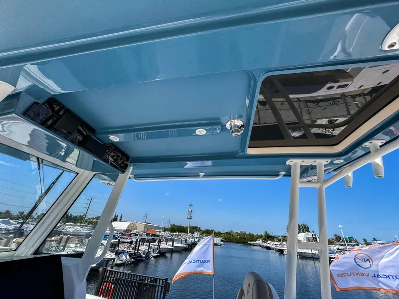 Slide: The Image of 2025 Edgewater 325CC boat interior with blue ceiling and marina view. - 14