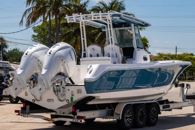 Slide: The Image of 2025 Edgewater 325CC boat on trailer with dual engines, parked outdoors. - 4