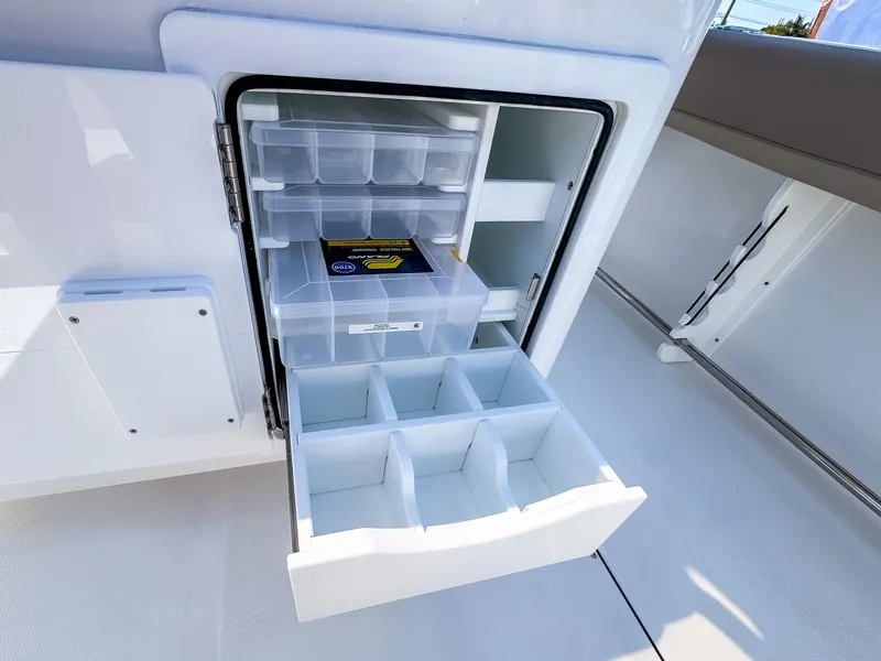 Slide: The Image of Open storage compartment on 2025 Edgewater 325CC boat with organized shelves and drawers. - 19