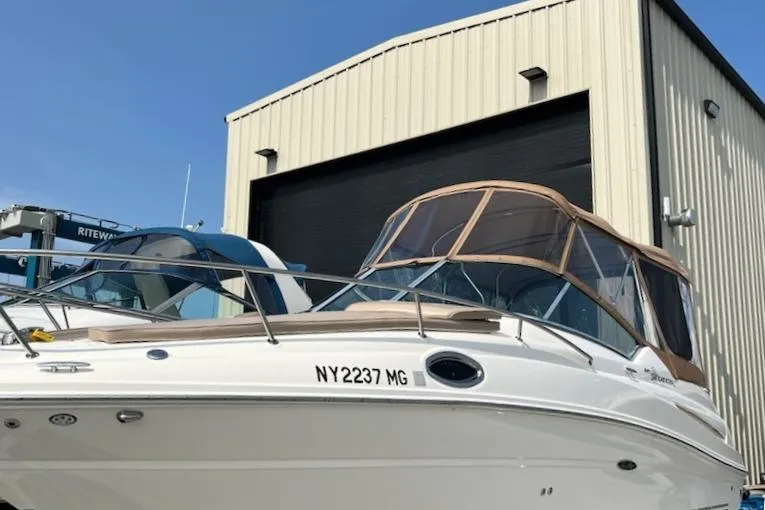 The Image of 2008 Sea Ray 240 Sundancer boat docked near a large storage building. - 0