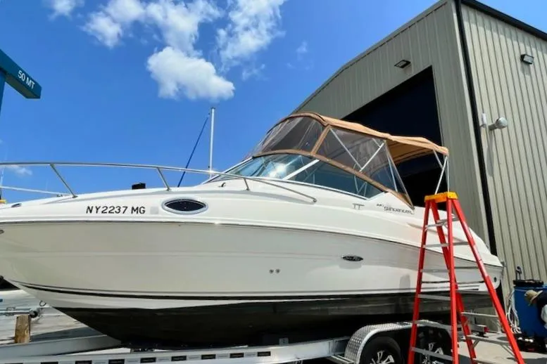 Slide: The Image of 2008 Sea Ray 240 Sundancer boat on trailer, blue sky background, near a building. - 2