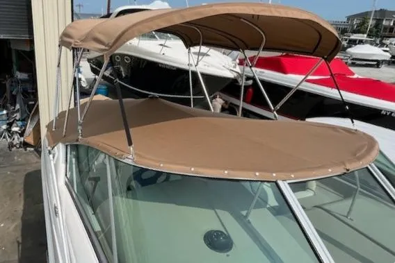 Slide: The Image of 2008 Sea Ray 240 Sundancer with tan canopy, docked alongside other boats. - 4
