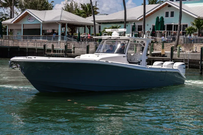 The Image of 2025 Edgewater 370CC boat cruising near waterfront buildings. - 0