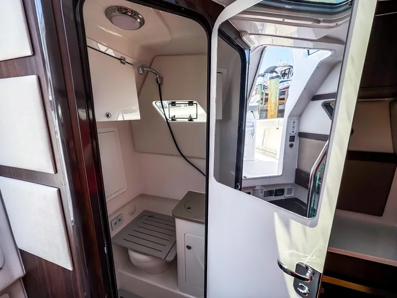 Slide: The Image of Interior of 2025 Edgewater 370CC boat featuring a compact bathroom with shower and toilet. - 24