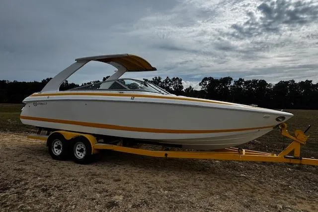 Slide: The Image of 2002 Cobalt 262 boat on trailer, parked outdoors under cloudy sky. - 2